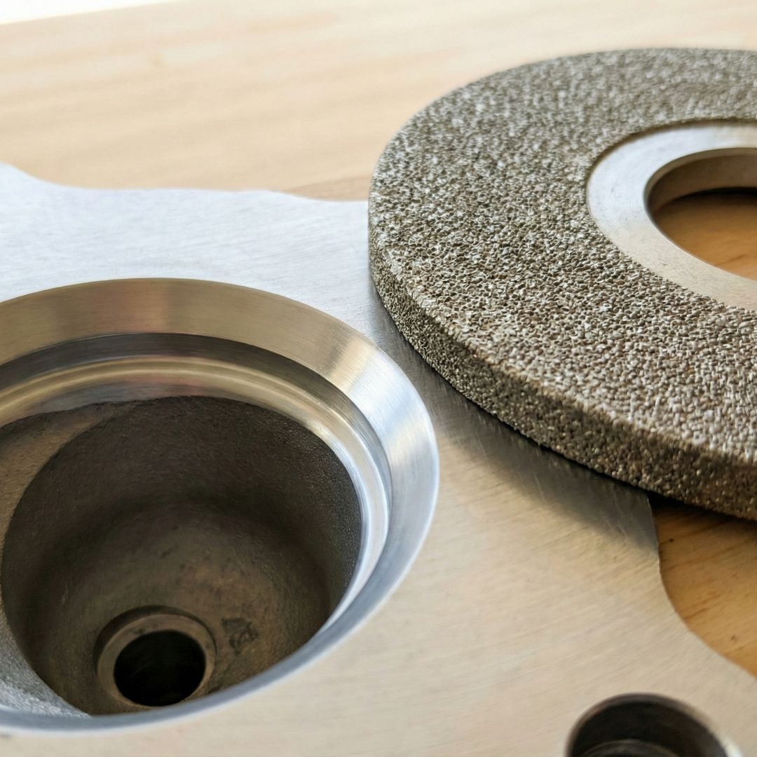 A close-up view of a diamond grinding wheel sitting next to a freshly machined valve seat.