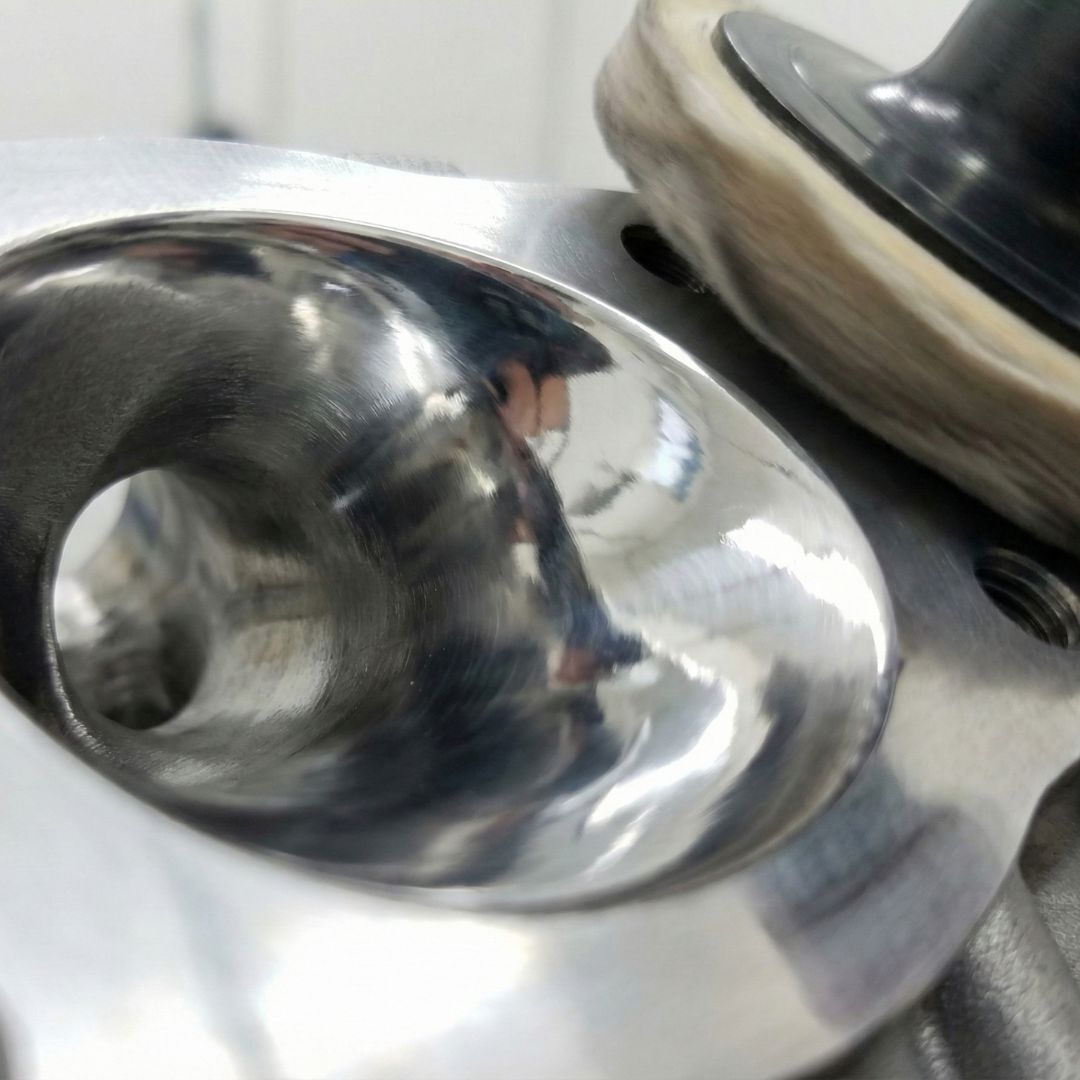 An extreme close-up showing the highly polished, mirror-finish interior of an engine exhaust port.